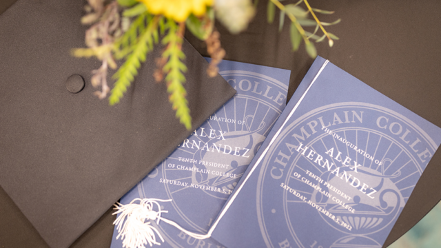 Programs from Hernandez’ inauguration placed on a table with a graduation cap and plant.